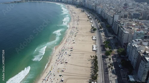 Wallpaper Mural Vídeo aéreo da praia de Copacabana, no Rio de Janeiro, Brasil, com o calçadão ondulado, areia dourada, mar azul, e movimentação de pessoas em um cenário tropical ensolarado Torontodigital.ca