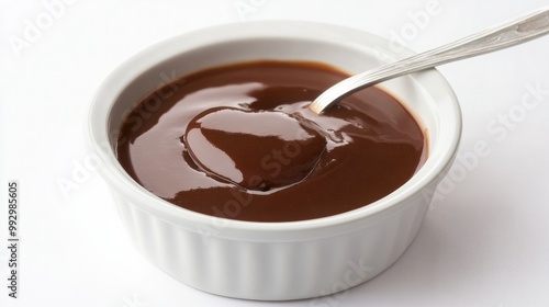 A small dish of rich brown gravy, with a spoon swirling through, placed on a bright white background for a warm and hearty food presentation.