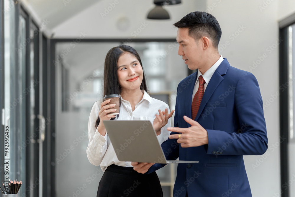 A professional setting where a man and woman engage in conversation while holding a laptop and a coffee cup. A professional setting where a man and woman engage in conversation while holding a laptop and a coffee cup.