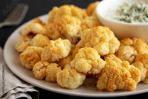 Homemade Buffalo Cauliflower with Blue Cheese Sauce on a Plate on a Black Background, side view. Close-up.