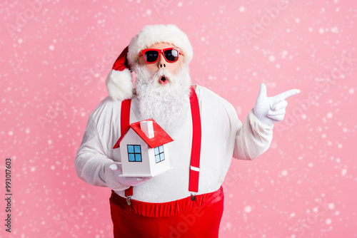 Portrait of his he nice attractive amazed stunned Santa holding in hands house demonstrating copy space offer bank property insurance novelty service isolated over pink pastel color background