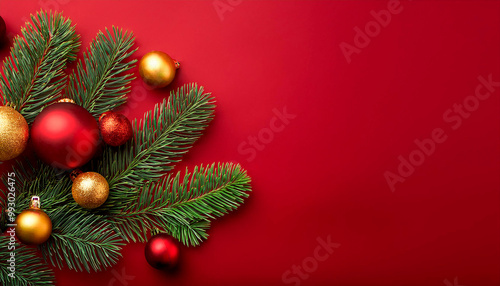 Christmas background with fir branches and red and gold baubles on red background