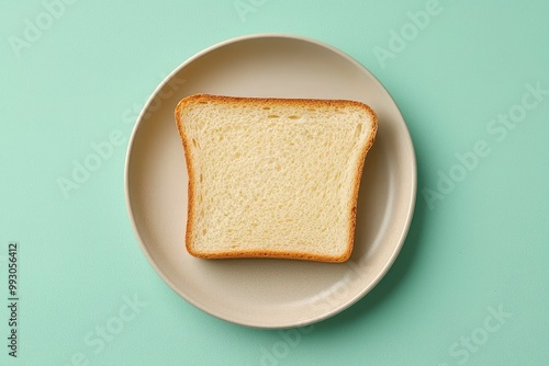 A Single Slice of Toast on a Beige Plate Against a Mint Green Background