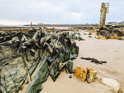 The rocky beach with concrete towers at Kilmore Quay, a fishing village in County Wexford, Ireland photo