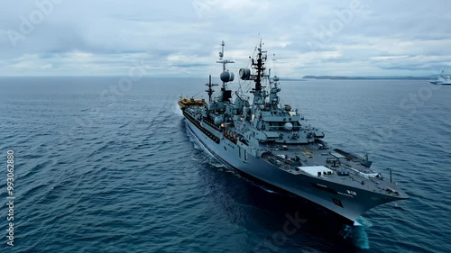 Military naval ship cruising on open sea under cloudy sky