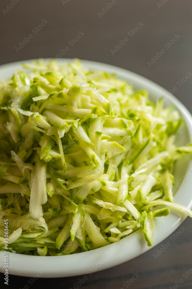 Shredded Zucchini in a White Bowl Close-Up on Dark Background Shredded Zucchini in a White Bowl Close-Up on Dark Background