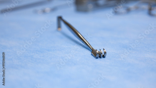 Surgical instruments Senn retractor used for surgery placed on blue background with blurred surgical equipment. Medical equipment. Medical science and surgery concept.