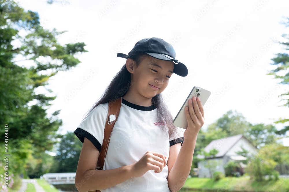Fototapeta premium スマートフォンで話をするランドセルを背負った小学生の女の子