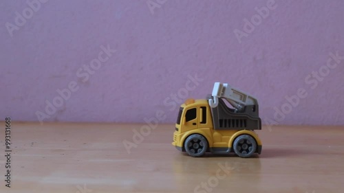Industrial mechanical yellow crane toy truck drive on wooden table, plaything for kid learning about construction site work and logistic work, copy space