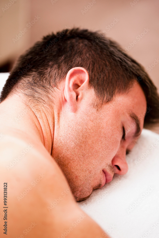 Close up of a man lying on his stomach with his eyes closed
Close up of a man lying on his stomach with his eyes closed