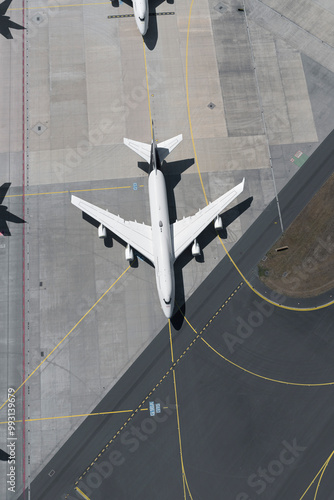 View from above airplane waiting on sunny airport runway
