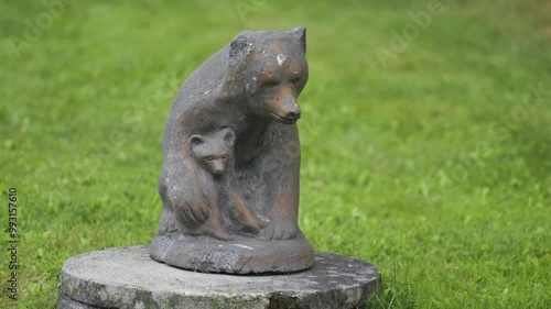 Carved wooden statue of the mother bear and her cub in the park of the Eveseter Hotel surrounded by lush grass and trees. A close-up parallax shot. photo