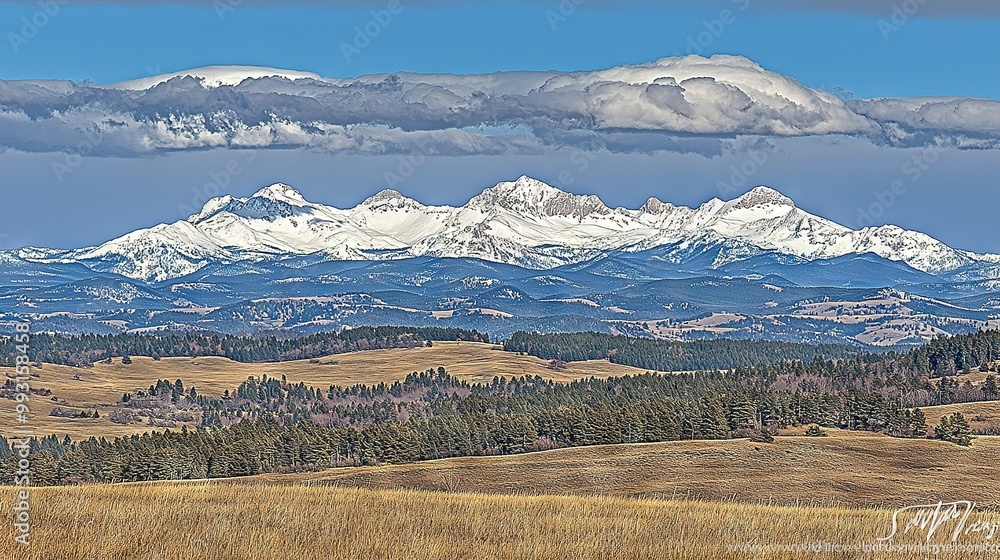 A mountain range with trees in the foreground and a blue sky with clouds in the background A mountain range with trees in the foreground and a blue sky with clouds in the background