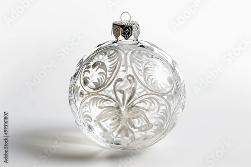 Delicate glass Christmas ornament is standing on a white background, its intricate silver ornaments catching the light photo