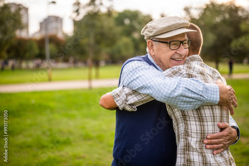 Happy grandfather and grandson are hugging and embracing in park.