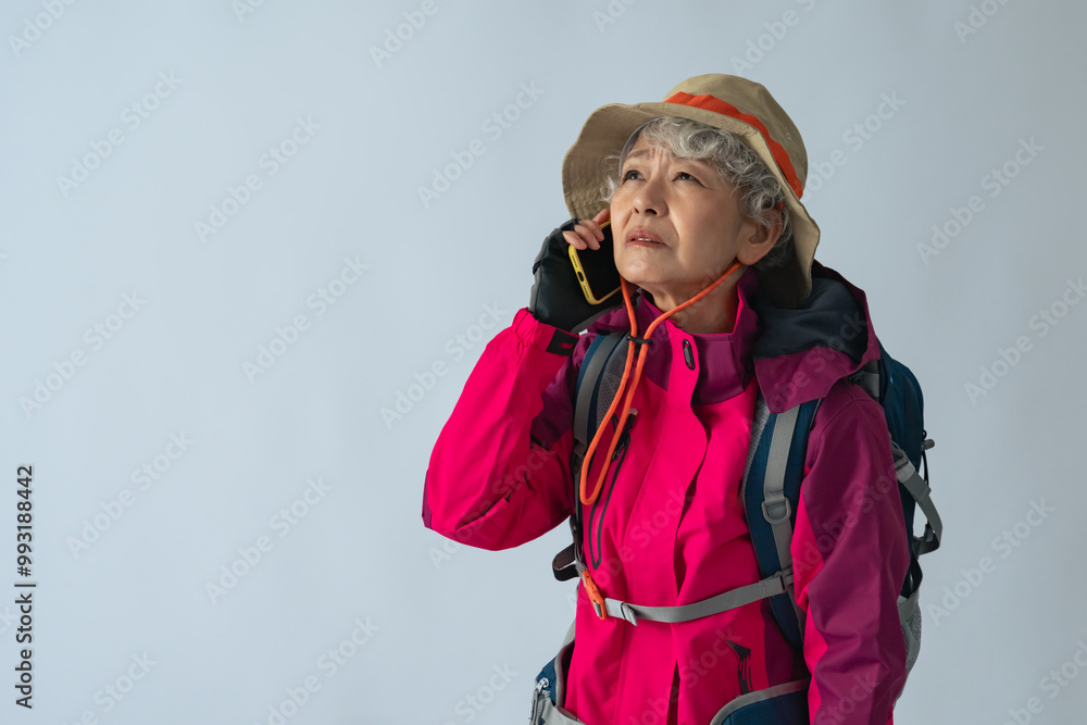 怯えてスマホで通話する登山服のシニア女性 怯えてスマホで通話する登山服のシニア女性