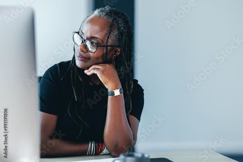 African business woman looking away with a pensive expression in her office