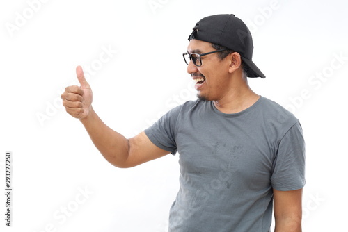 Asian man Looking proud, smiling doing thumbs up gesture to the side photo