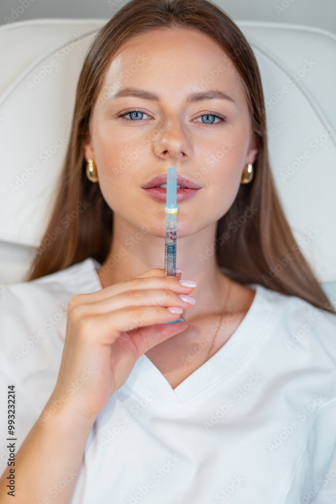 Beautiful healthy woman holding filler injection near lips. Beauty and health. Lip augmentation, creative idea Beautiful healthy woman holding filler injection near lips. Beauty and health. Lip augmentation, creative idea