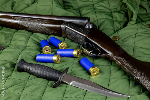 Vintage Shotgun with Cartridges and Hunting Knife on a Quilted Outdoor Coat photo