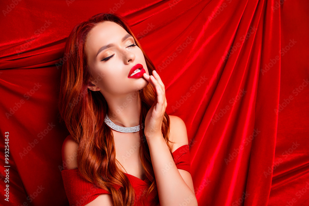 Naklejka premium Rich attractive girl with closed eyes touch fingers lips teasing feel passionate on red linen texture background