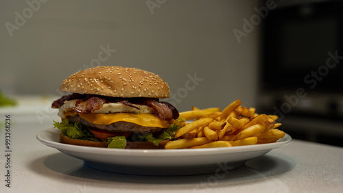 Sabrosa hamburguesa con queso, tocino y huevo sobre un pan de sésamo, acompañada de crujientes papas fritas. Plato de comida rápida listo para servir.