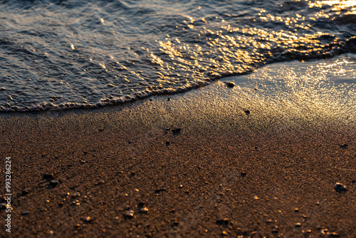 Waves lap the seashore and cover the small stones.