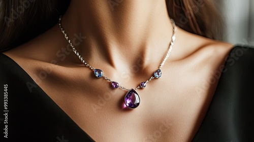 A detailed view of an amethyst and aquamarine necklace on a womanaes neck, the silver catching the light against her smooth skin.