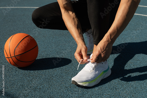 Фотография Close up basketball player tying sports shoes in basketball court outdoors