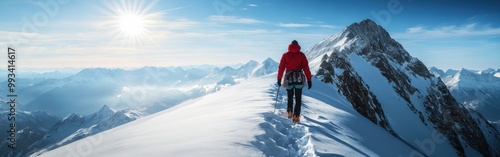 Climber in red jacket trekking through the snowy Alps under bright sunlight