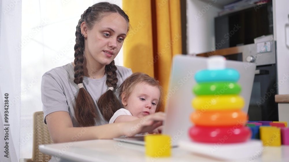 Mom works and lifestyle looks after the child. happy childhood dream concept for a little child. young mother works remotely via laptop during quarantine and plays with blocks with her small child Mom works and lifestyle looks after the child. happy childhood dream concept for a little child. young mother works remotely via laptop during quarantine and plays with blocks with her small child