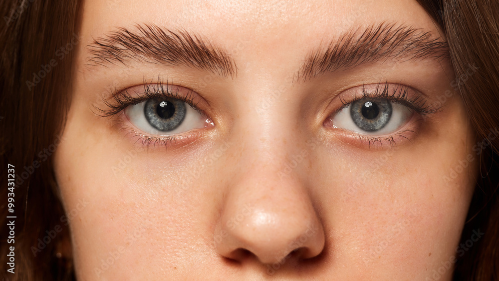 Fototapeta premium Close-up of blue eyes with neatly groomed eyebrows, highlighting natural beauty and facial care. Young female model with well-kept skin. Concept of beauty, fashion, appearance, self care. Ad