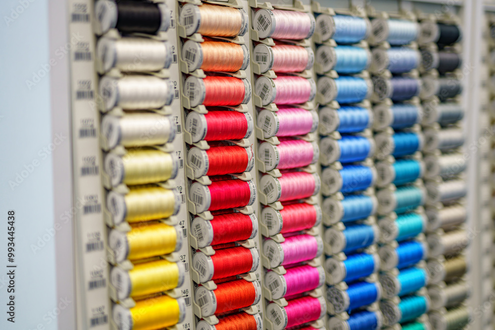 Fototapeta premium Close-up of colored sewing threads of different colors on display in a sewing shop. It is multicolored and made of textile sewing threads.