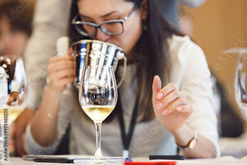 Professional female sommelier uses a spittoon to spit out the tasted wine during tasting. photo