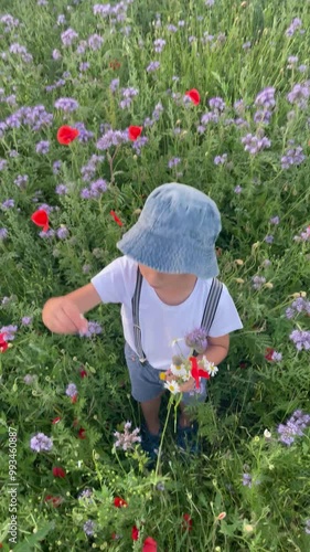 Beautiful school child in a flower field on sunset, playing with airplane and vintage suitcase