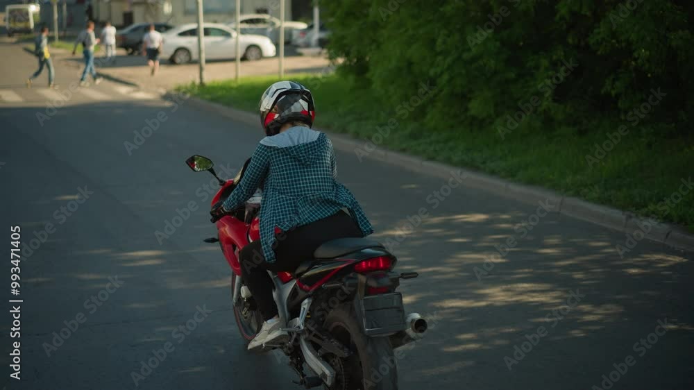 A rider on a red power bike cruising along a serene urban road, the rider is wearing a checkered shirt and helmet, heading towards a crosswalk with pedestrians in the distance A rider on a red power bike cruising along a serene urban road, the rider is wearing a checkered shirt and helmet, heading towards a crosswalk with pedestrians in the distance