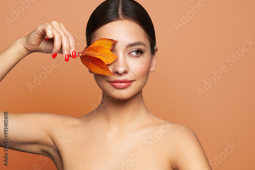 Portrait of beautiful young woman with autumn leafs. Healthy clean fresh skin natural make up beauty eyes and red nails photo