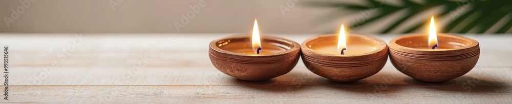 Three clay oil lamps with flickering flames, arranged on a wooden surface, creating a serene atmosphere. Three clay oil lamps with flickering flames, arranged on a wooden surface, creating a serene atmosphere.