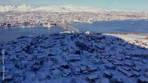 Soaring above the snow covered landscape of Norwegian town of Tromso in winter season. Picturesque coastal scenery, icy fjords and the unique blend of urban life and Arctic wilderness. photo