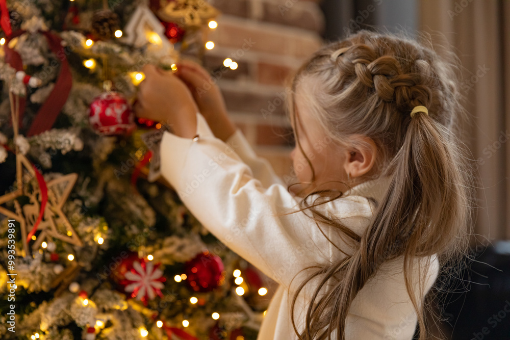 Side view cute little child girl in white warm sweater is decorating Christmas tree in living room at home. Merry Christmas and Happy New year winter holidays. High quality photo Side view cute little child girl in white warm sweater is decorating Christmas tree in living room at home. Merry Christmas and Happy New year winter holidays. High quality photo