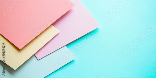 Overlapping pastel paper sheets in pink, yellow, peach, and light blue tones on a turquoise background, creating a clean and modern design.