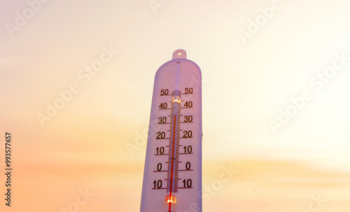 Thermometer for measuring outdoor air temperature. Meteorological device for observing and measuring the weather. Weather forecast. Thermometer on sunset background. Hot weather, drought in summer.