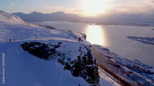 Aerial of snow covered landscape of Norwegian town of Troms in winter. Floya viewpoint with people, icy fjord and urban arctic life photo