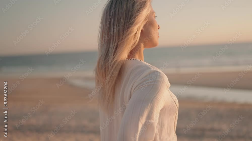 A blonde woman in a white dress relaxes on the beach at sunset, breathing in the fresh air and enjoying the peace and quiet. A blonde woman in a white dress relaxes on the beach at sunset, breathing in the fresh air and enjoying the peace and quiet.