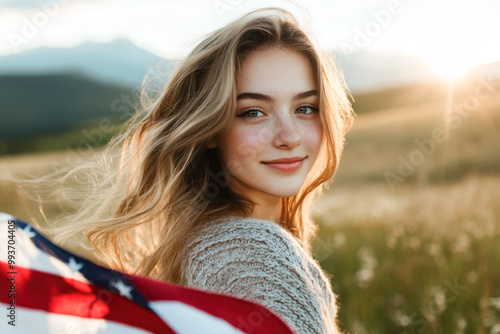 A beautiful woman in her 20s-30s is standing with the U.S. flag against a beautiful mountain landscape and a sunset