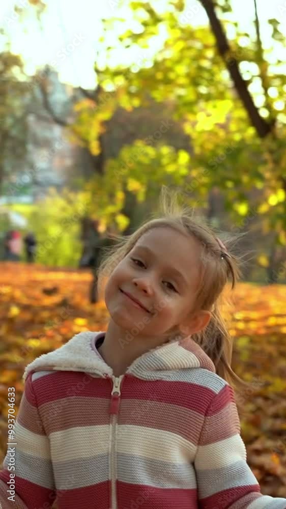 Camera rotates around happy girl with bouquet maple leaves in autumn park at sunset. Child plays outdoors. Leisure in nature in October. Vertical shot