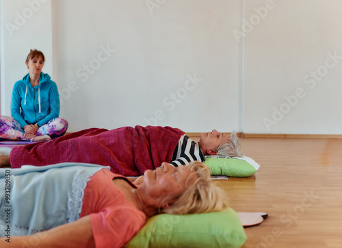 A group of senior women rests on the floor in a studio after an intense workout and stretching session. photo