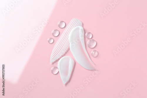 Smears of different cosmetic products on color background, top view