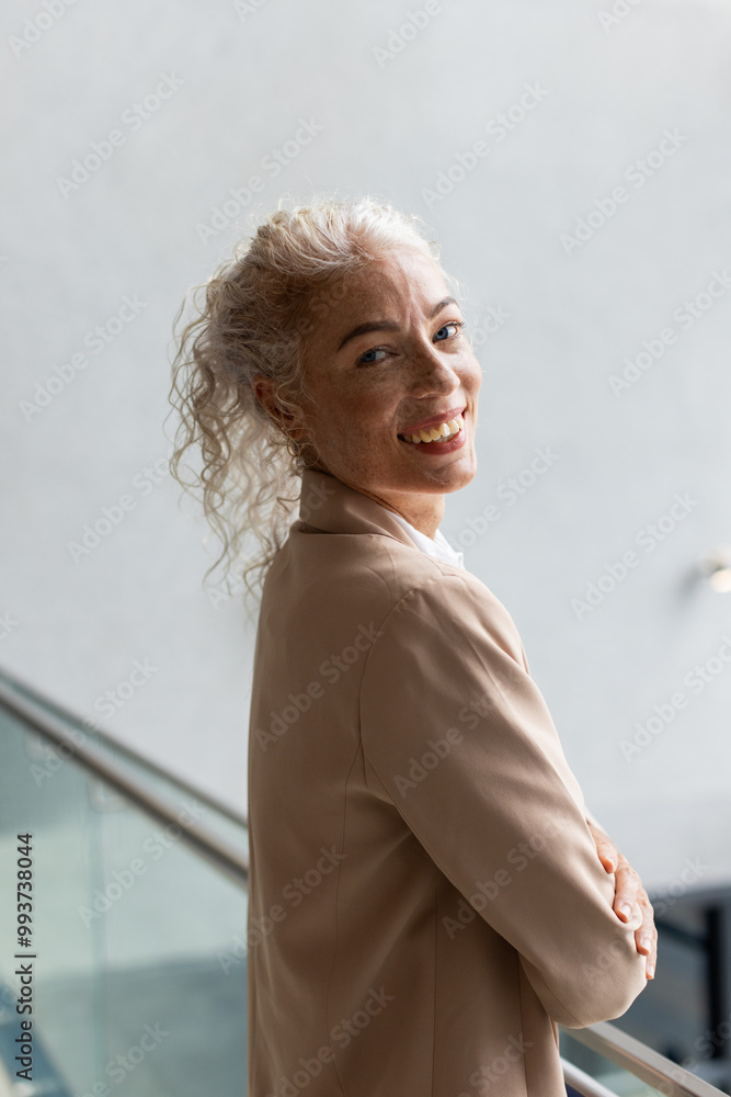 Fototapeta premium Smiling woman in business attire standing with arms crossed, looking confident