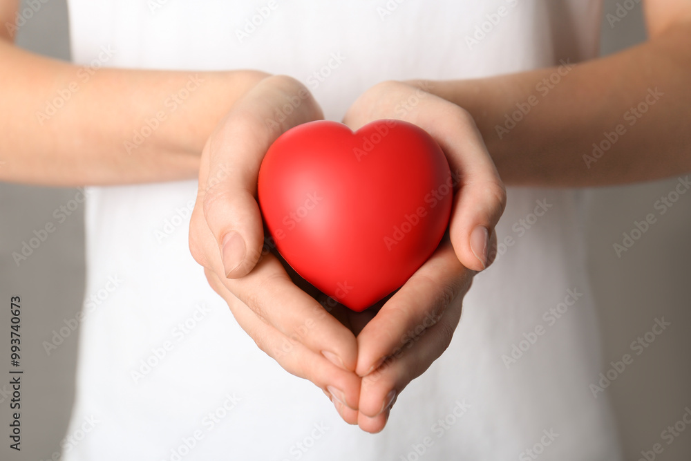 Woman holding red heart on grey background, closeup Woman holding red heart on grey background, closeup